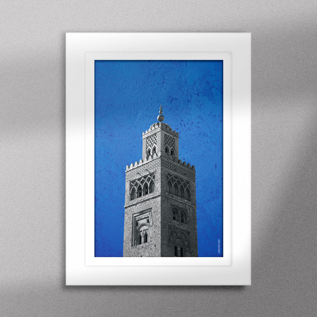 Tableau décoratif représentant la Koutoubia de Marrakech sur un fond bleu, encadré dans un cadre blanc - Format A5.
